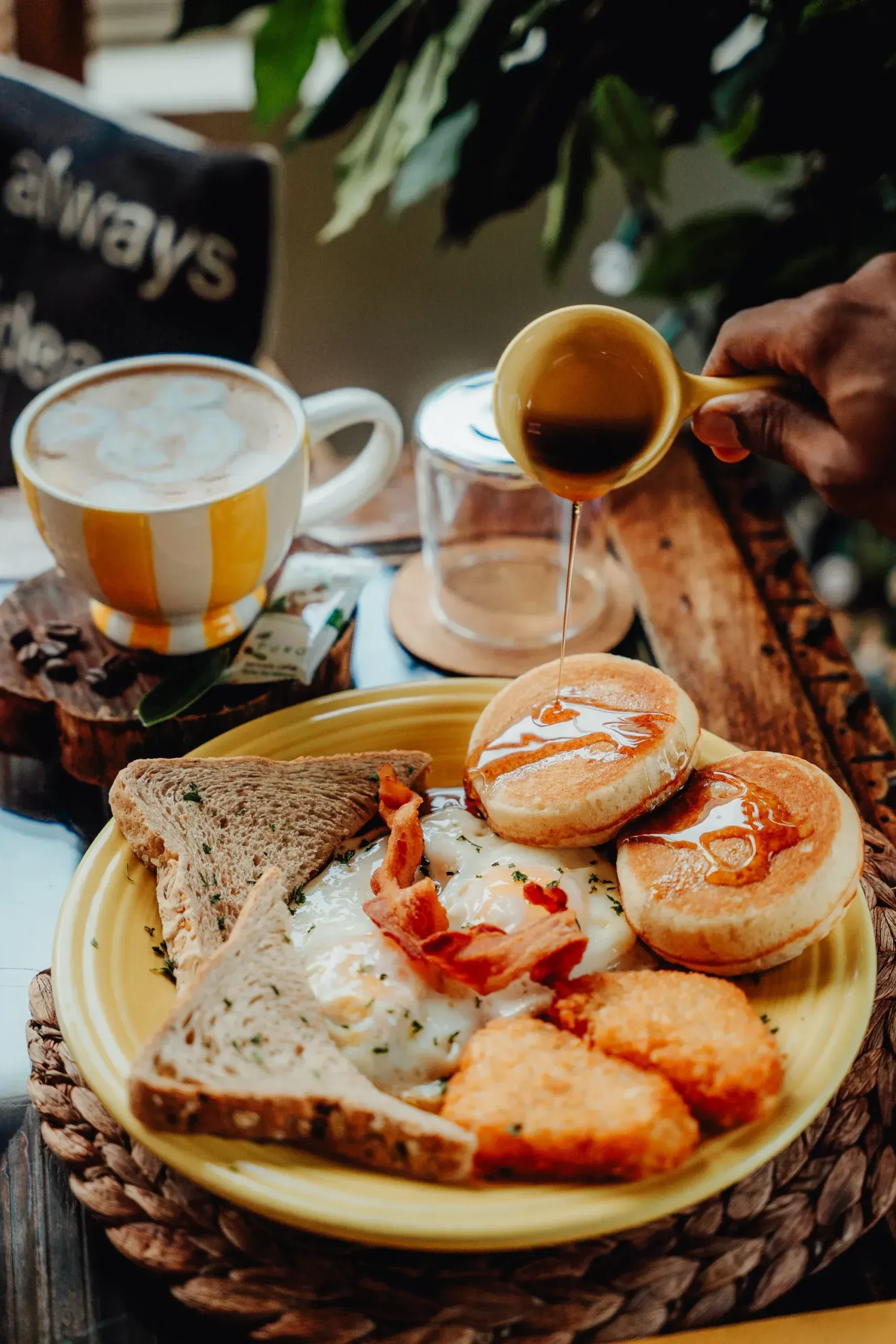 A person is pouring coffee into a cup next to a plate of food.