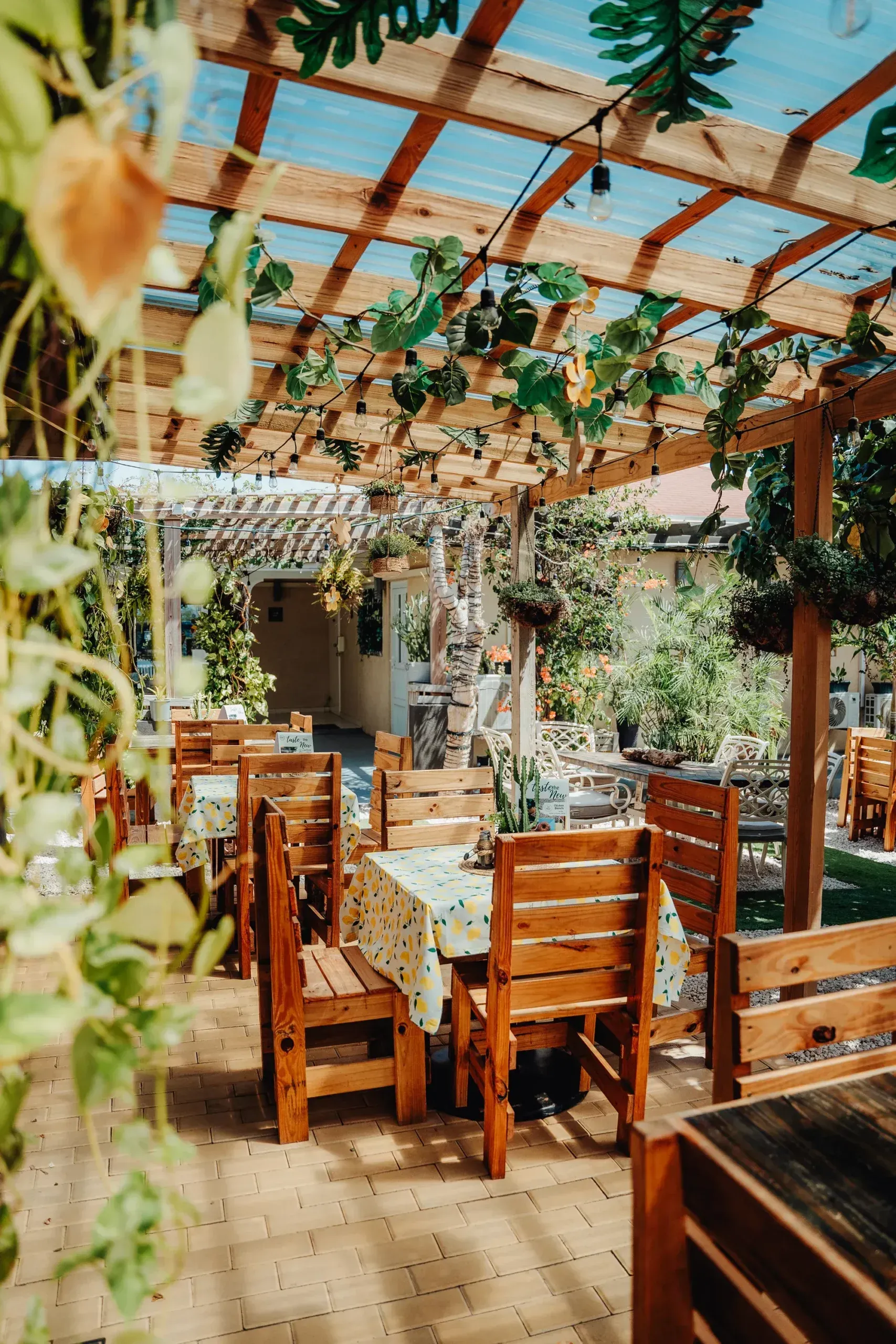 A restaurant with wooden tables and chairs under a wooden pergola.