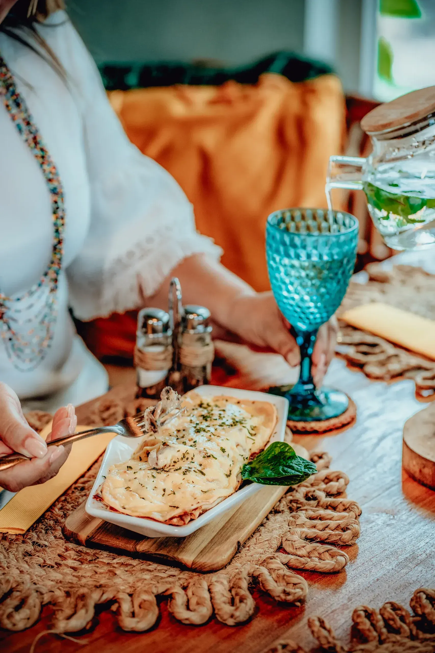 A woman is sitting at a table with a plate of food and a glass of wine.