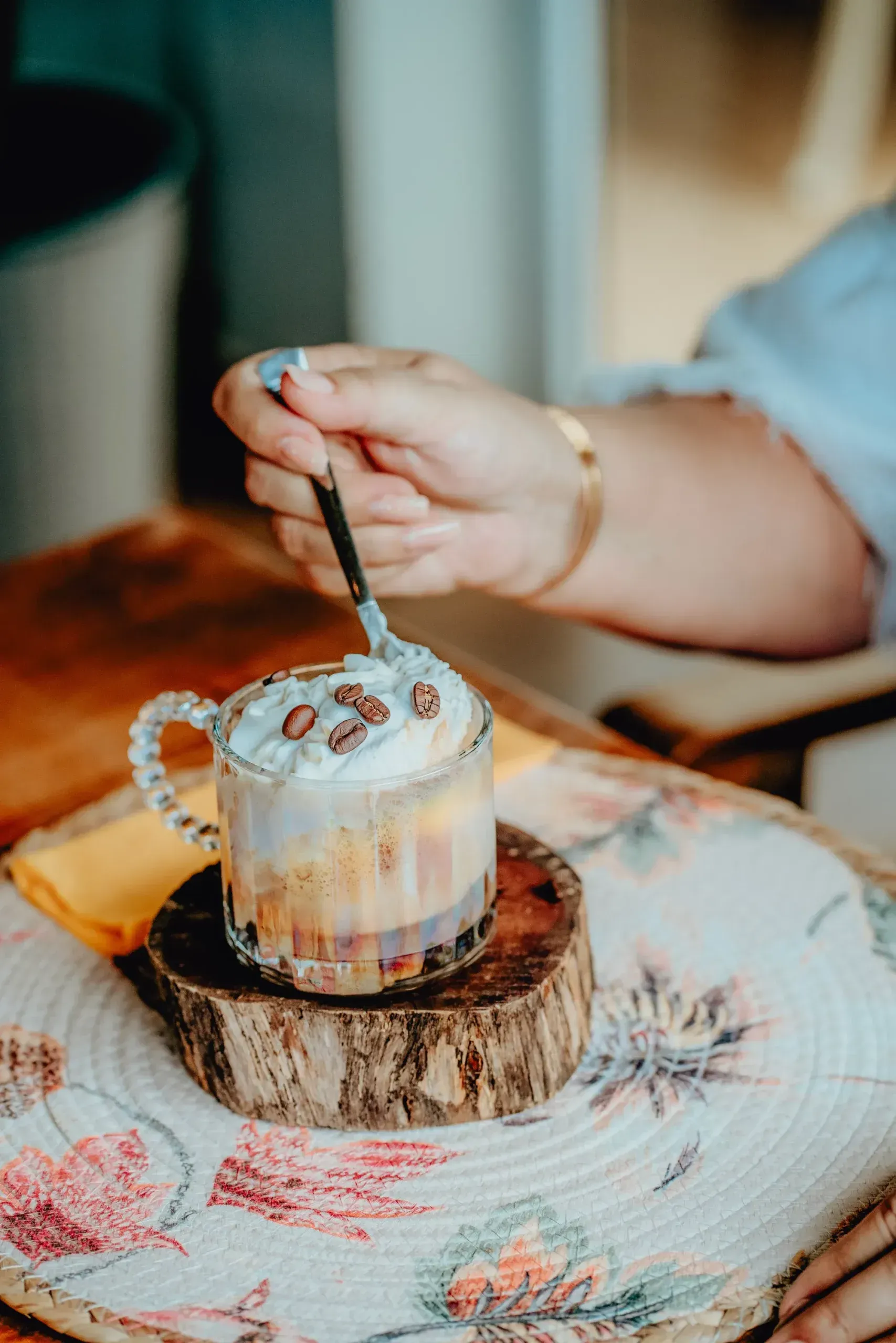 A person is stirring a cup of coffee with a spoon.