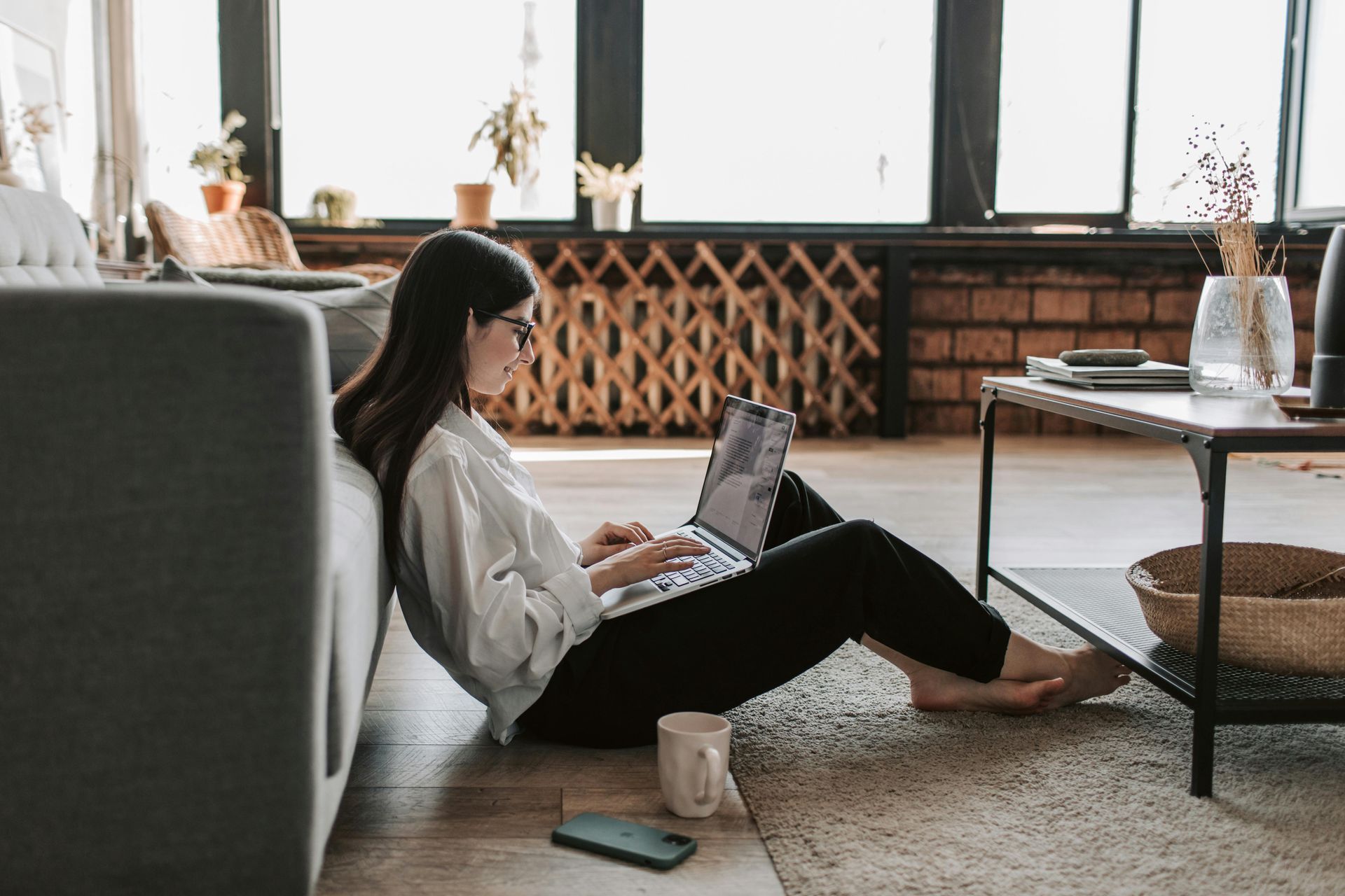 A woman is sitting on the floor using a laptop computer.