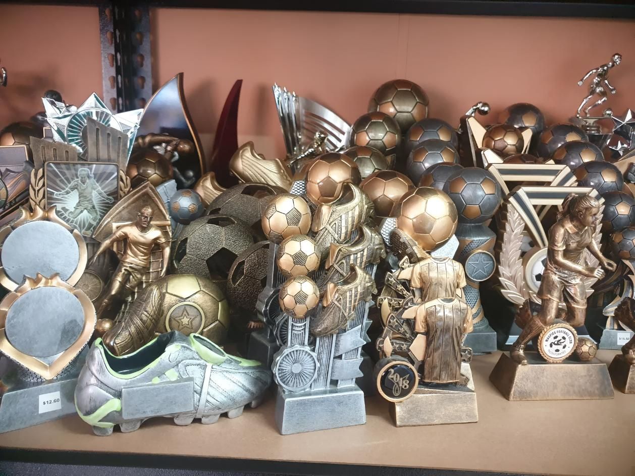 A Shelf Full Of Trophies Including A Soccer Trophy — Ace Wholesale Trophies & Engraving In Bakers Creek, QLD