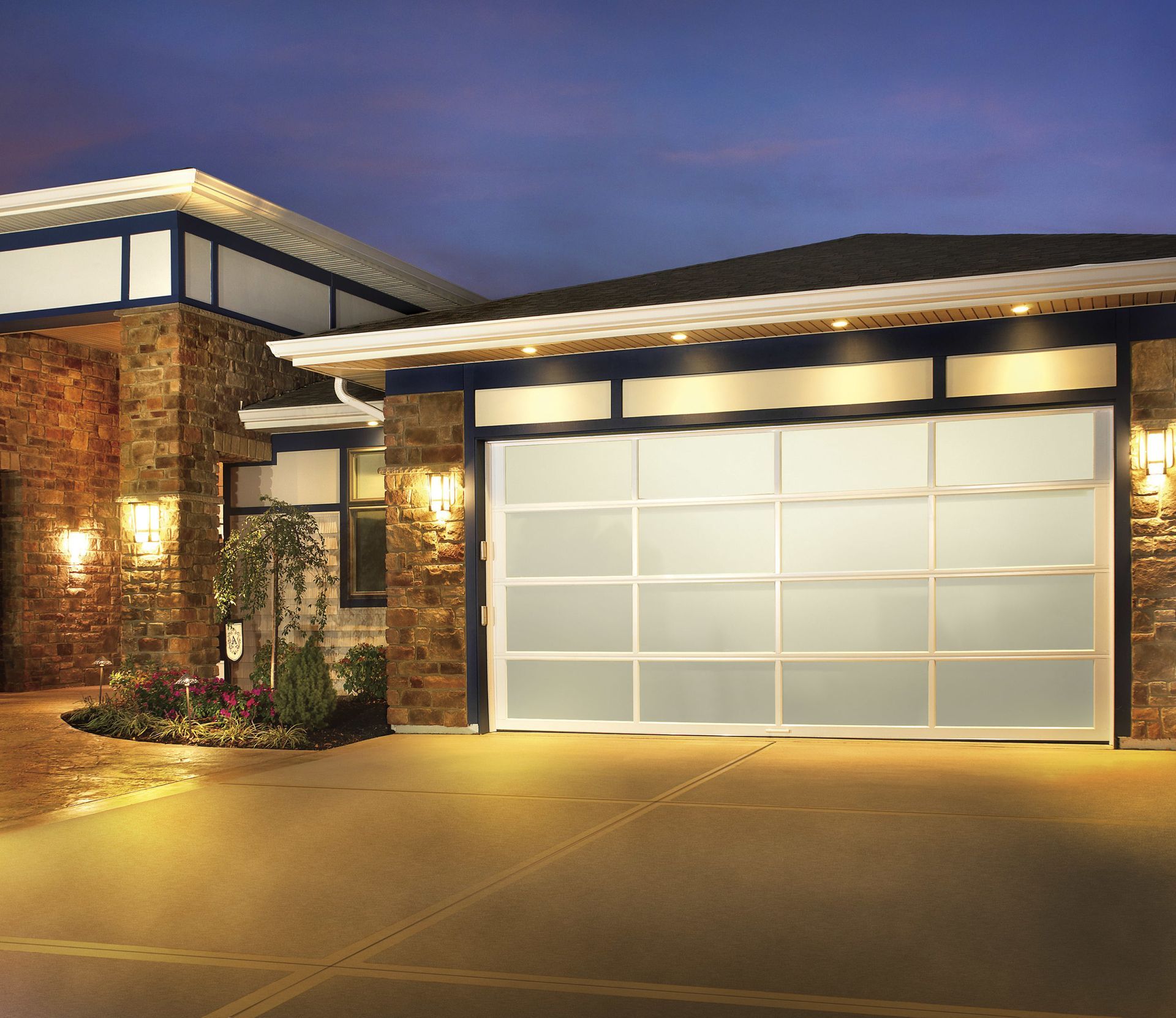 a house with a large garage door is lit up at night