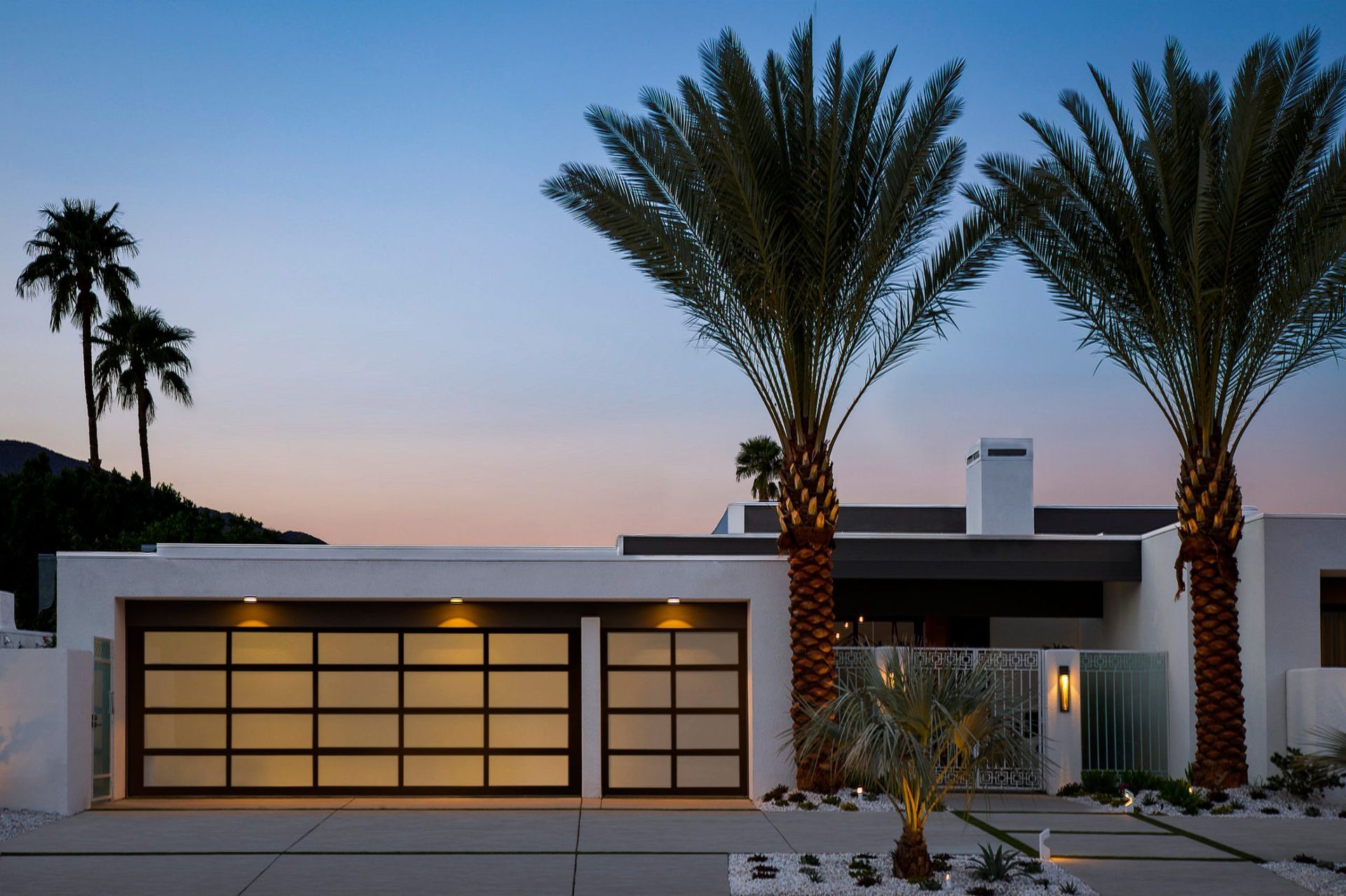 a modern house with palm trees in front of it