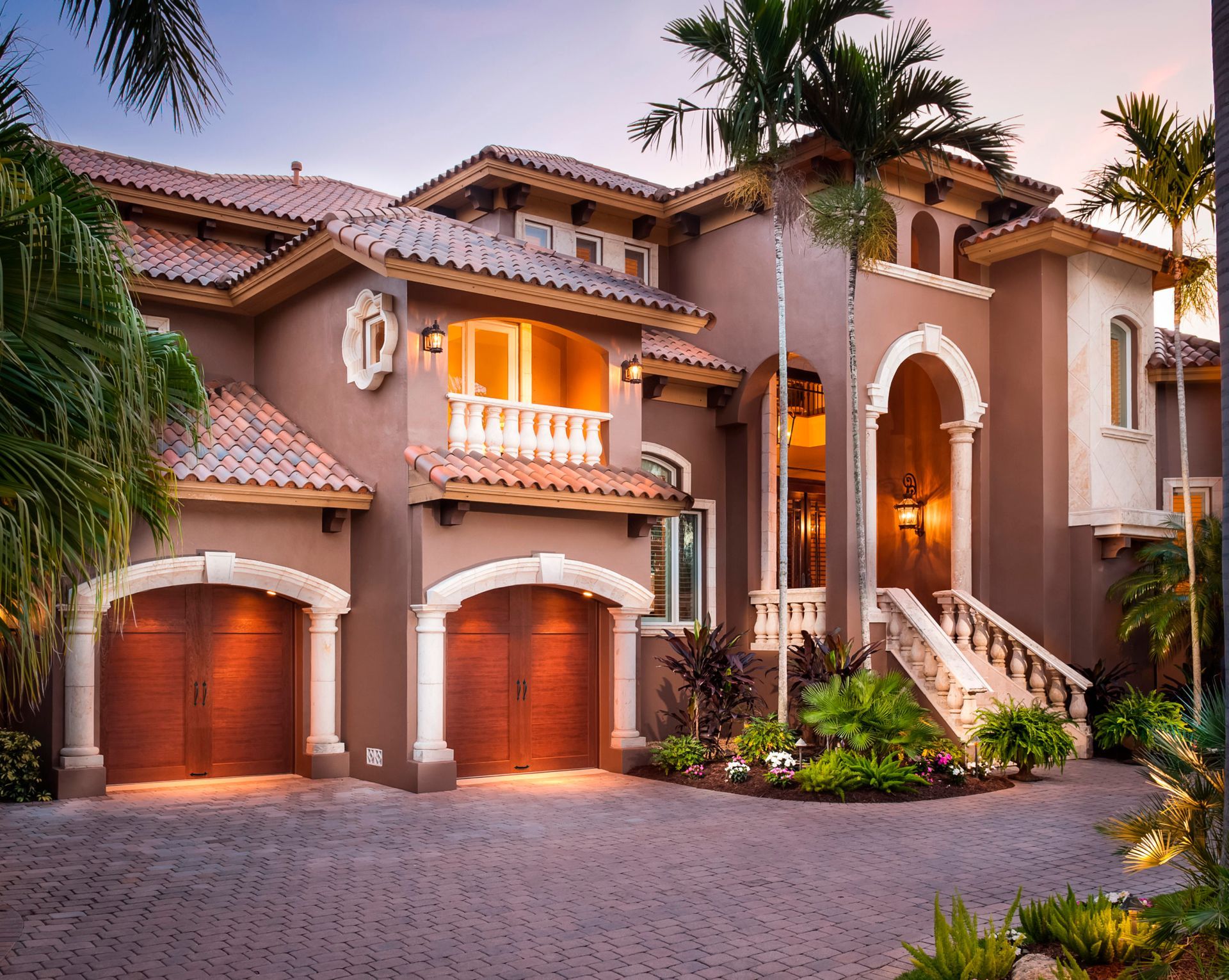 a large house with a lot of garage doors and palm trees in front of it