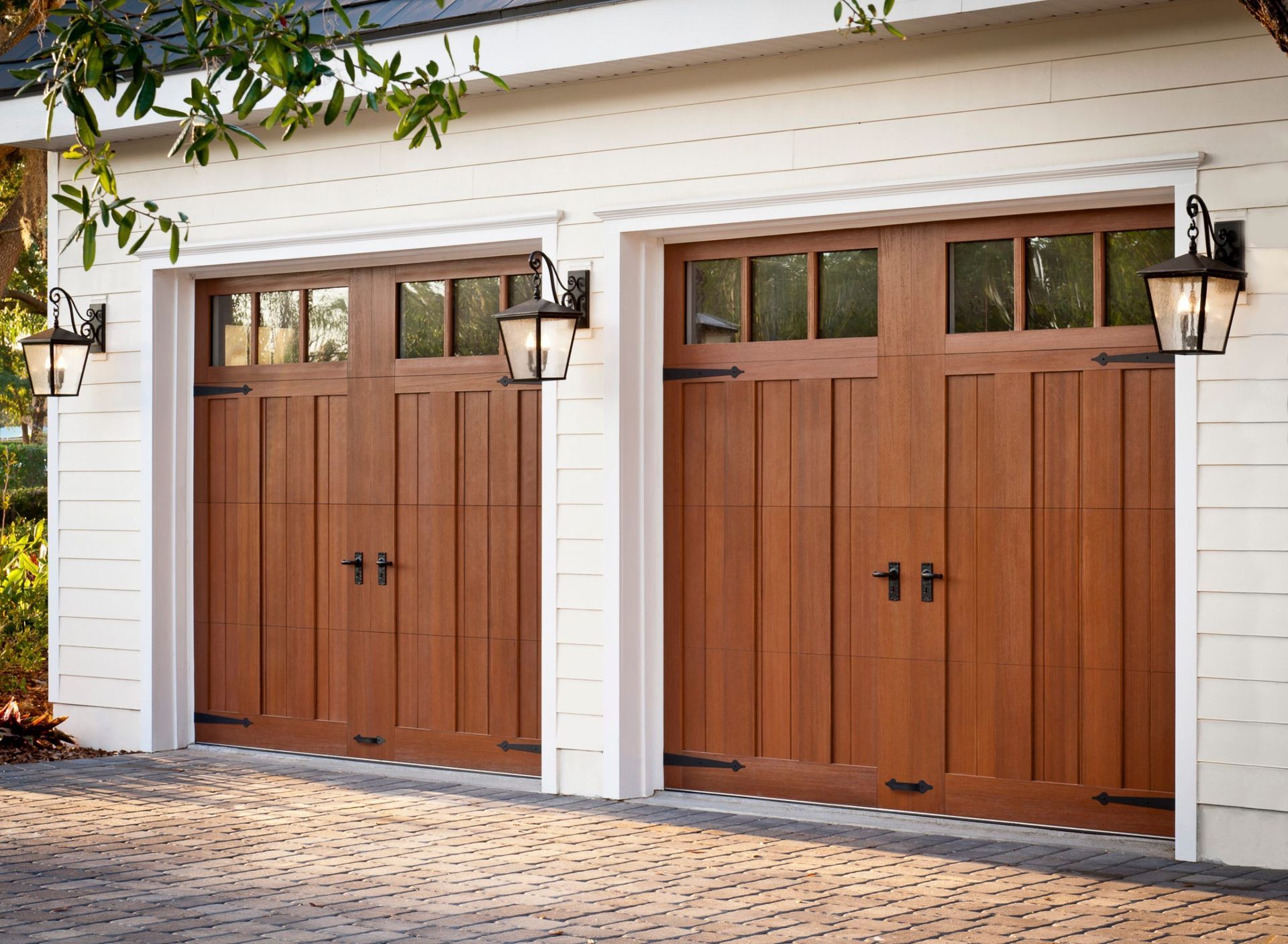 a pair of wooden garage doors on a white house .