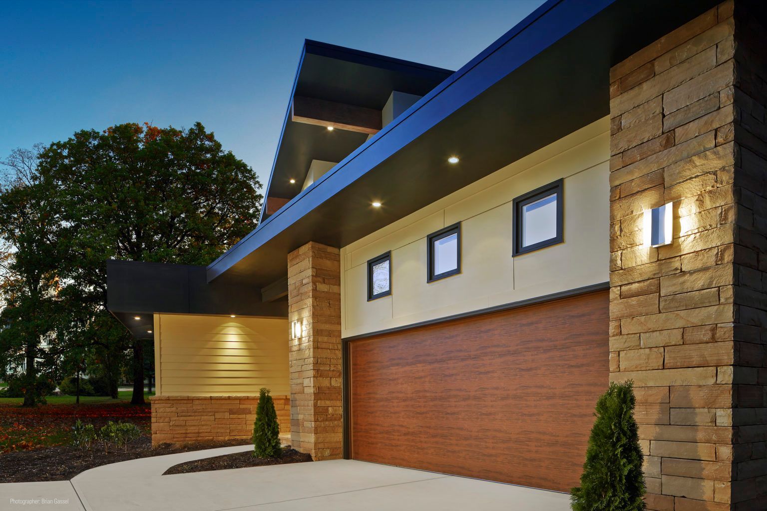 a modern house with a wooden garage door and a brick wall
