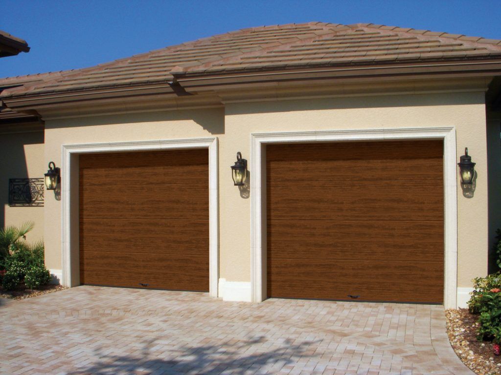 a house with two garage doors and a brick driveway