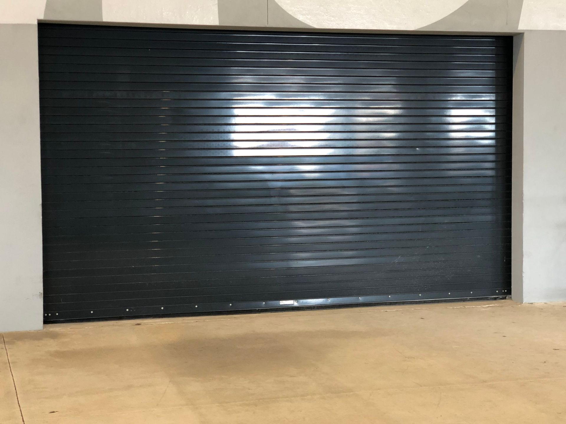 a black garage door is sitting on the side of a building .
