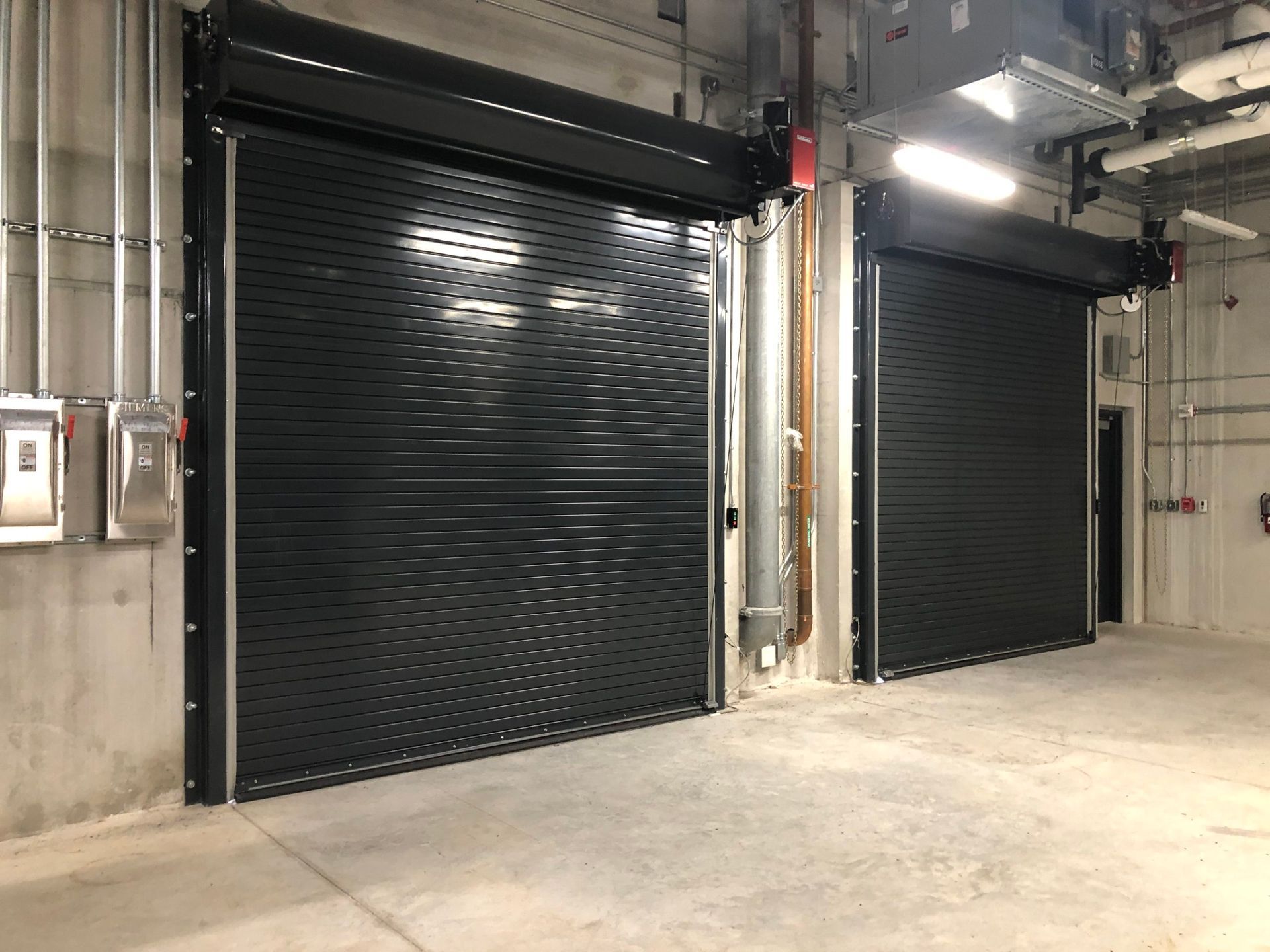 two black garage doors are open in a large room .