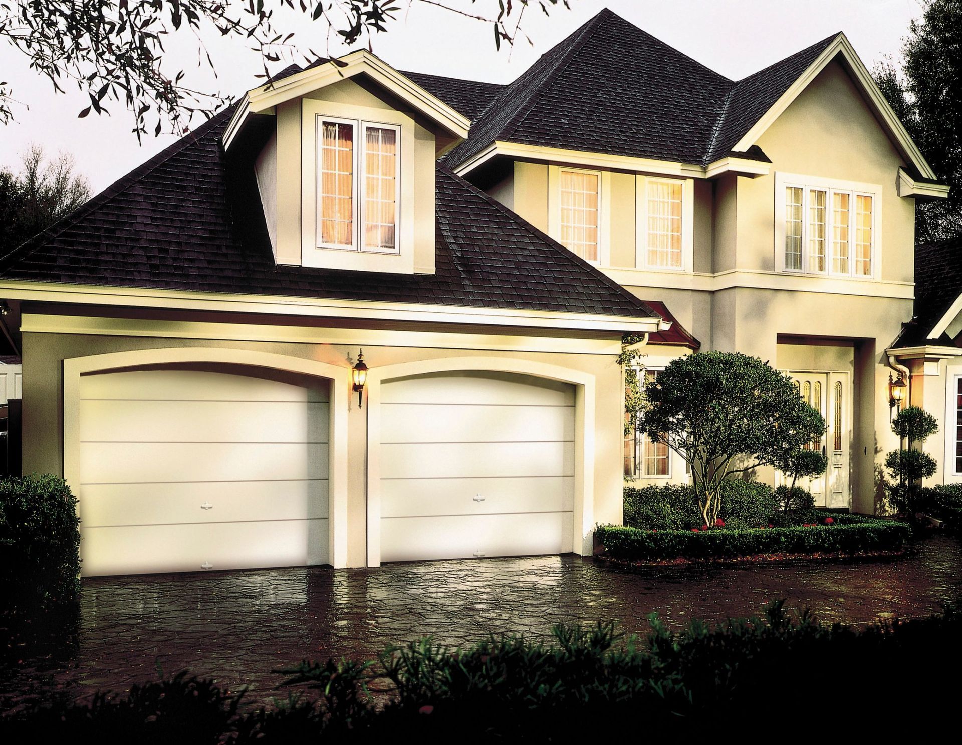 a large house with two garage doors and a black roof