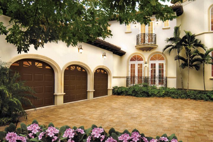 a large house with three garage doors and flowers in front of it