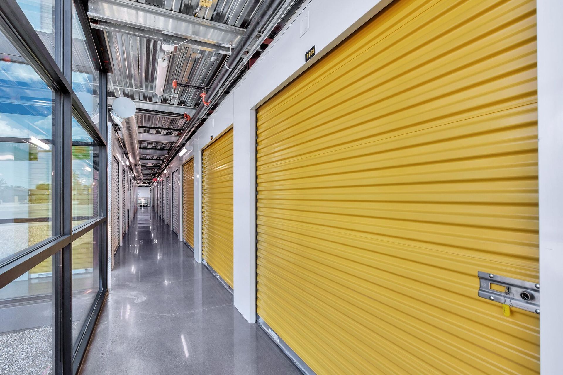 a long hallway with yellow garage doors in a building .