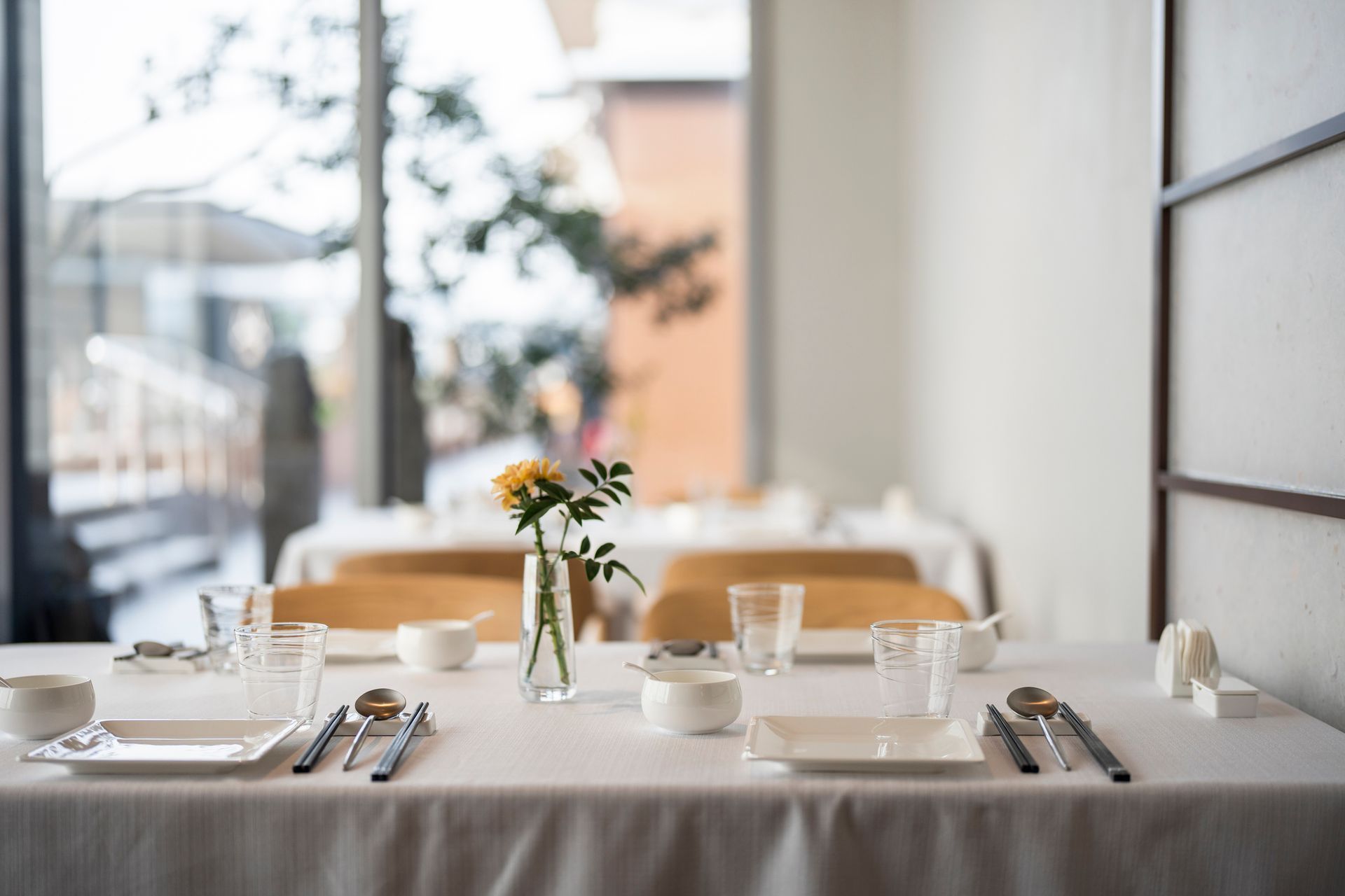 Una tavola apparecchiata per un pasto con posate, piatti e un vaso di fiori.