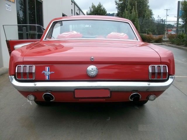A red mustang is parked in a parking lot