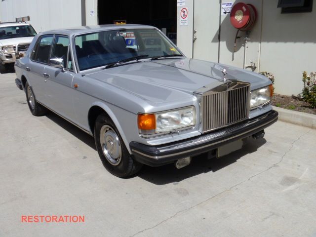 A silver rolls royce is parked in a parking lot