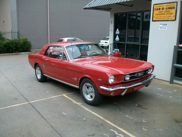 A red car is parked in front of a car-o-liner sign