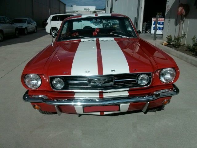 A red mustang with white stripes on the hood