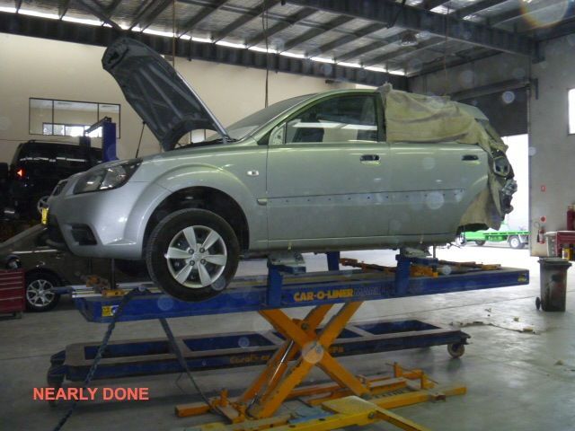 A silver car is sitting on a lift in a garage nearly done