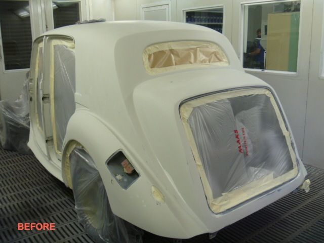 A white car is sitting in a paint booth before being painted