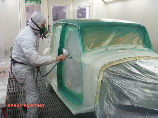 A man is spray painting a car in a paint booth