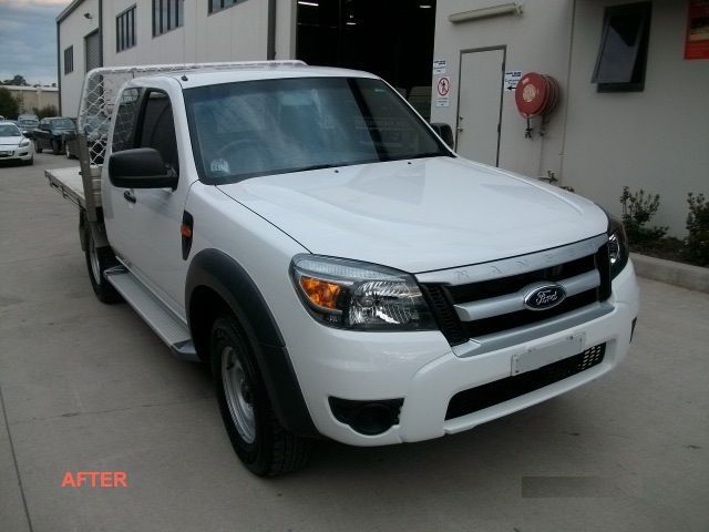 A white ford truck is parked in front of a building