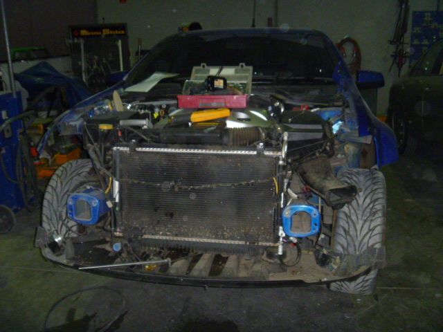 A blue car is being worked on in a garage