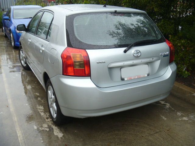 A silver toyota corolla is parked in a parking lot
