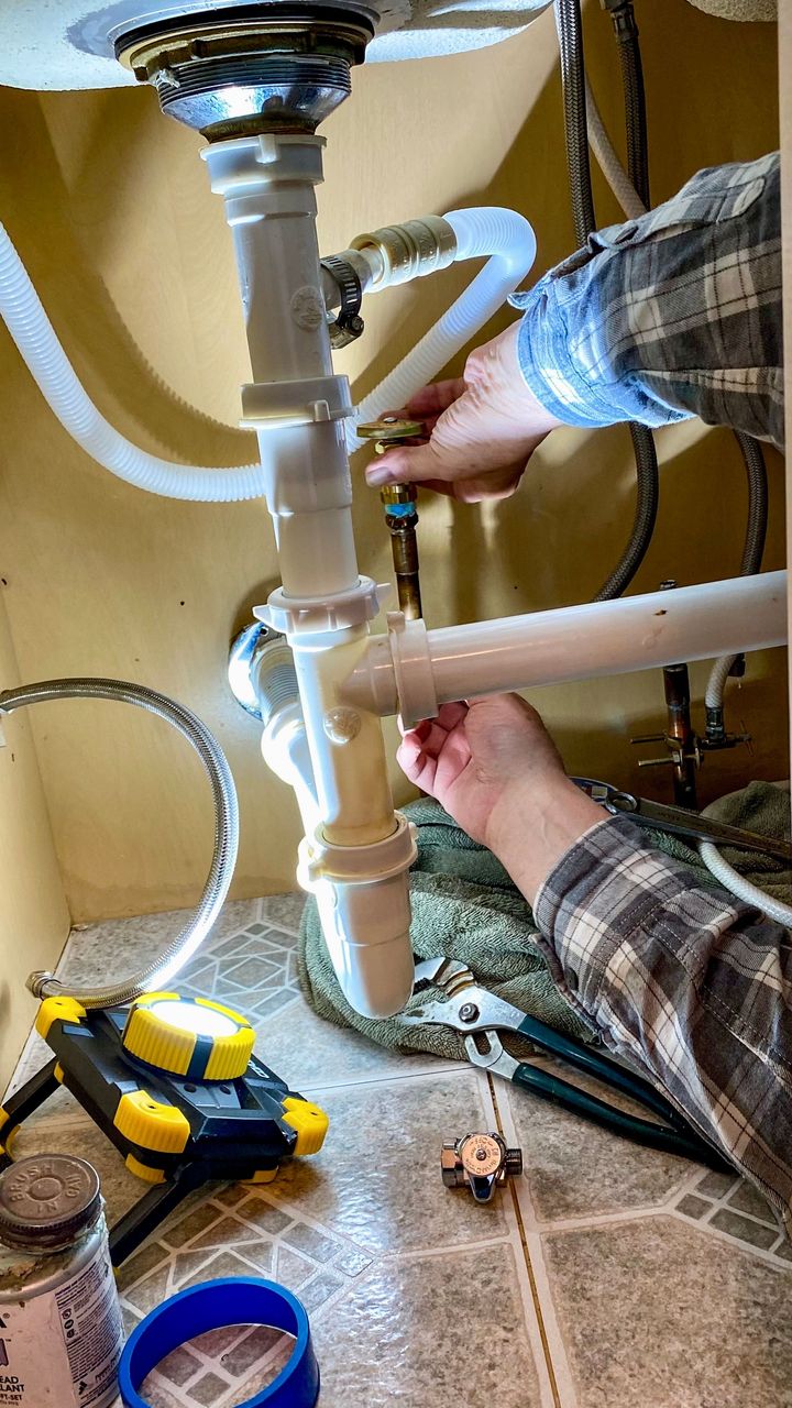 plumber at work repairing pipes in home basement 