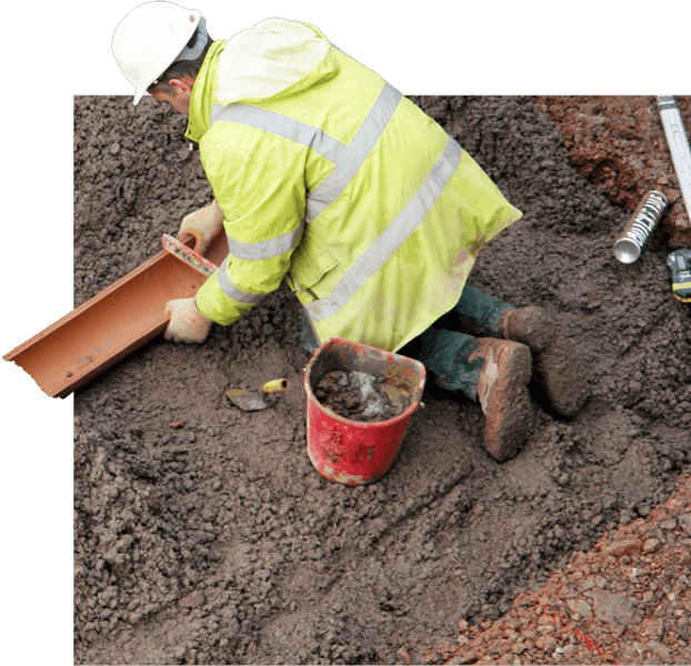 worker making space in dirt for new pipe 