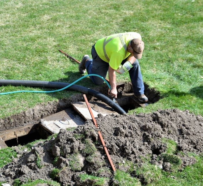plumber working on buried cable in a trench.