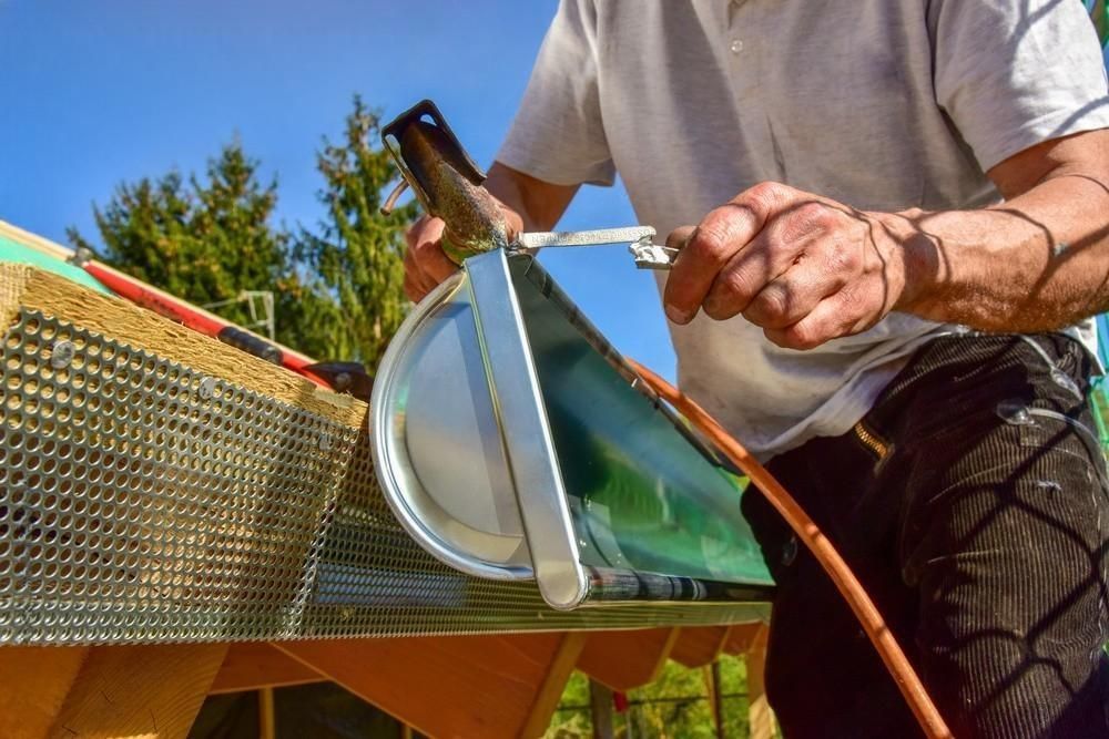 A man is cutting a piece of metal with a pair of scissors.