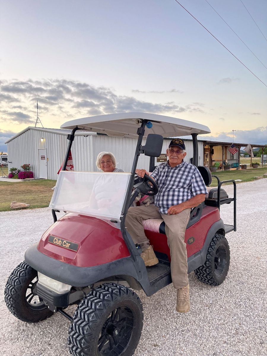 A man and a woman are sitting in a golf cart.