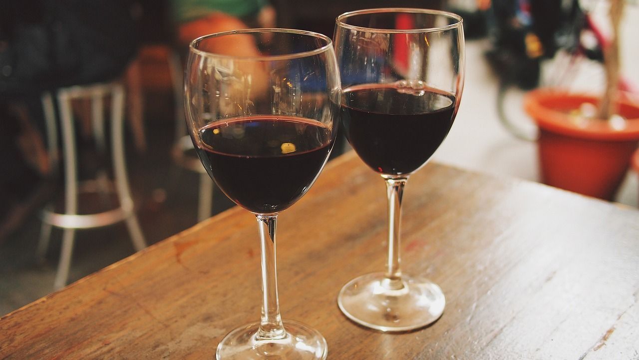 Two glasses of red wine are sitting on a wooden table.
