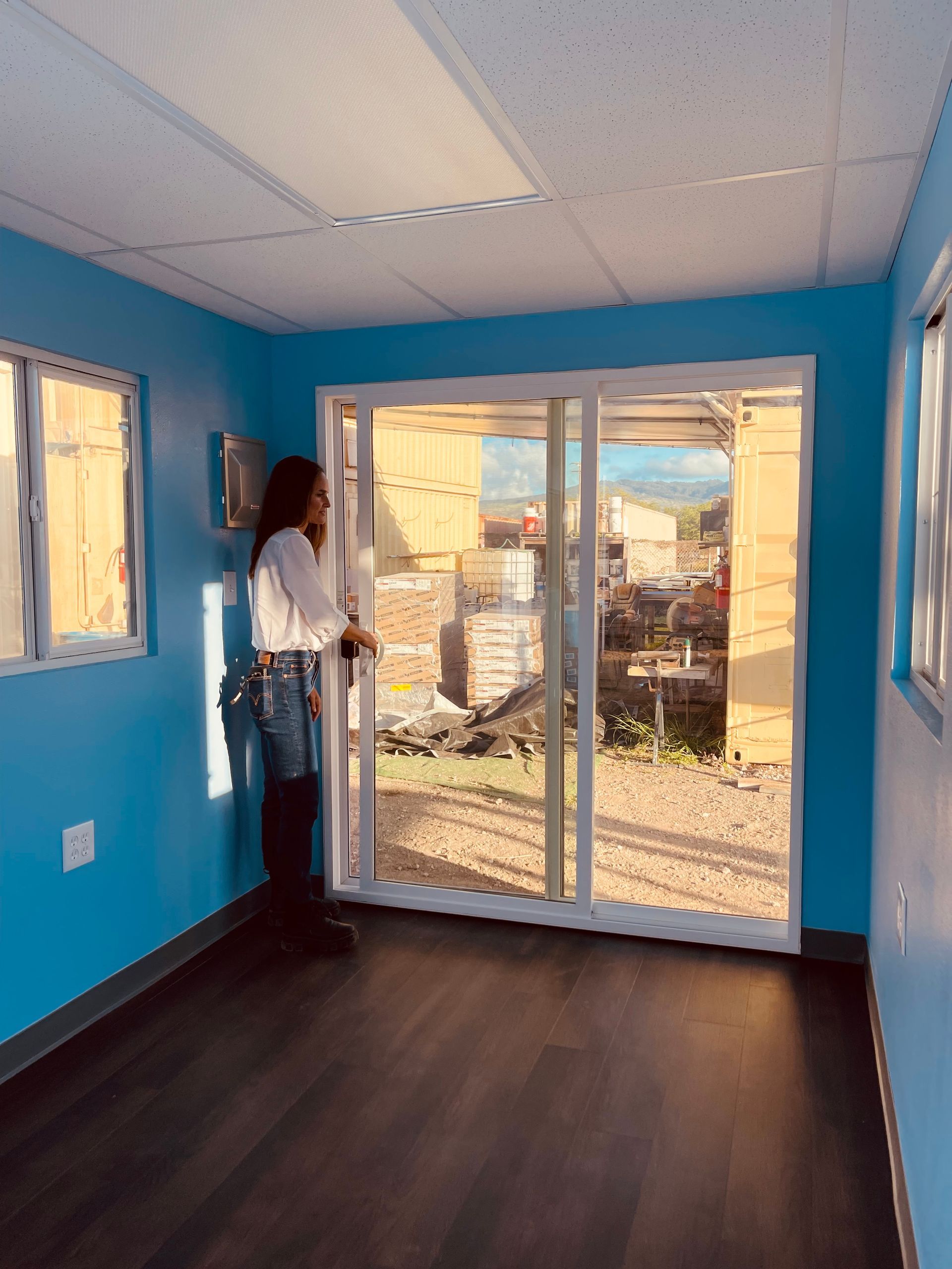 Allison standing by the custom sliding glass doors installed in a 20' mobile container office.