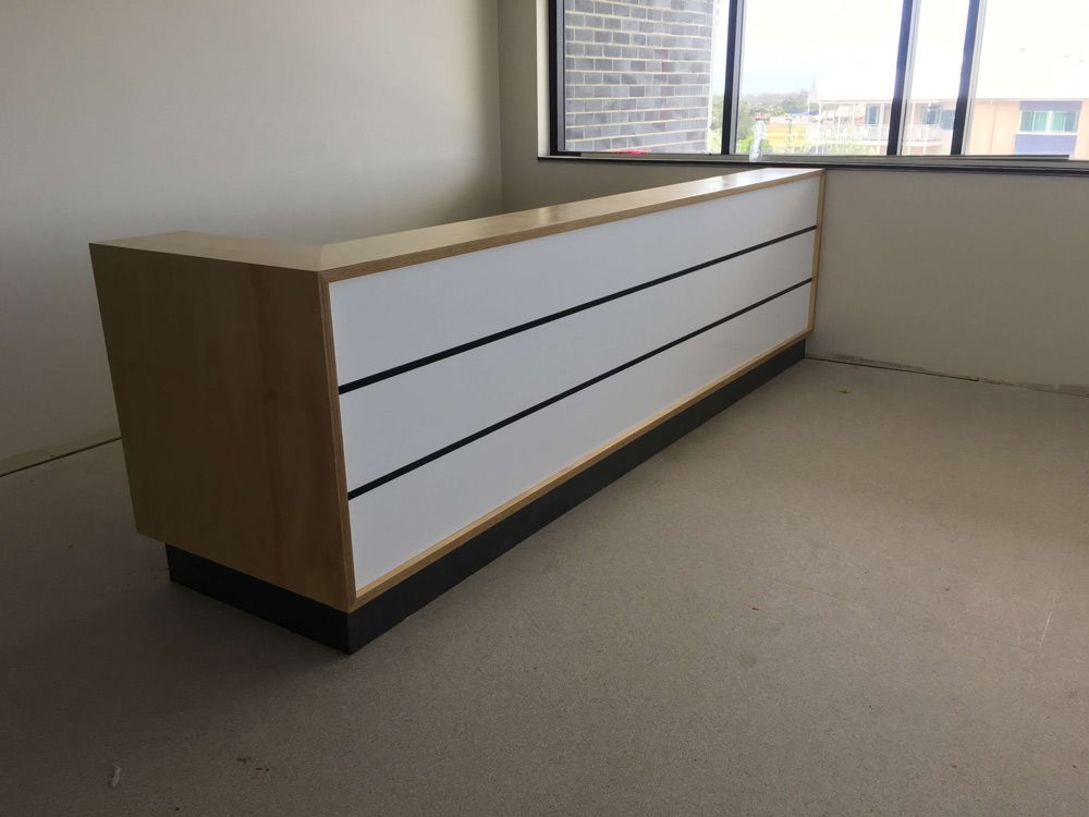 A Long Wooden Desk is Sitting in a Room Next to a Window — GC Joinery in Sunshine Acres, QLD