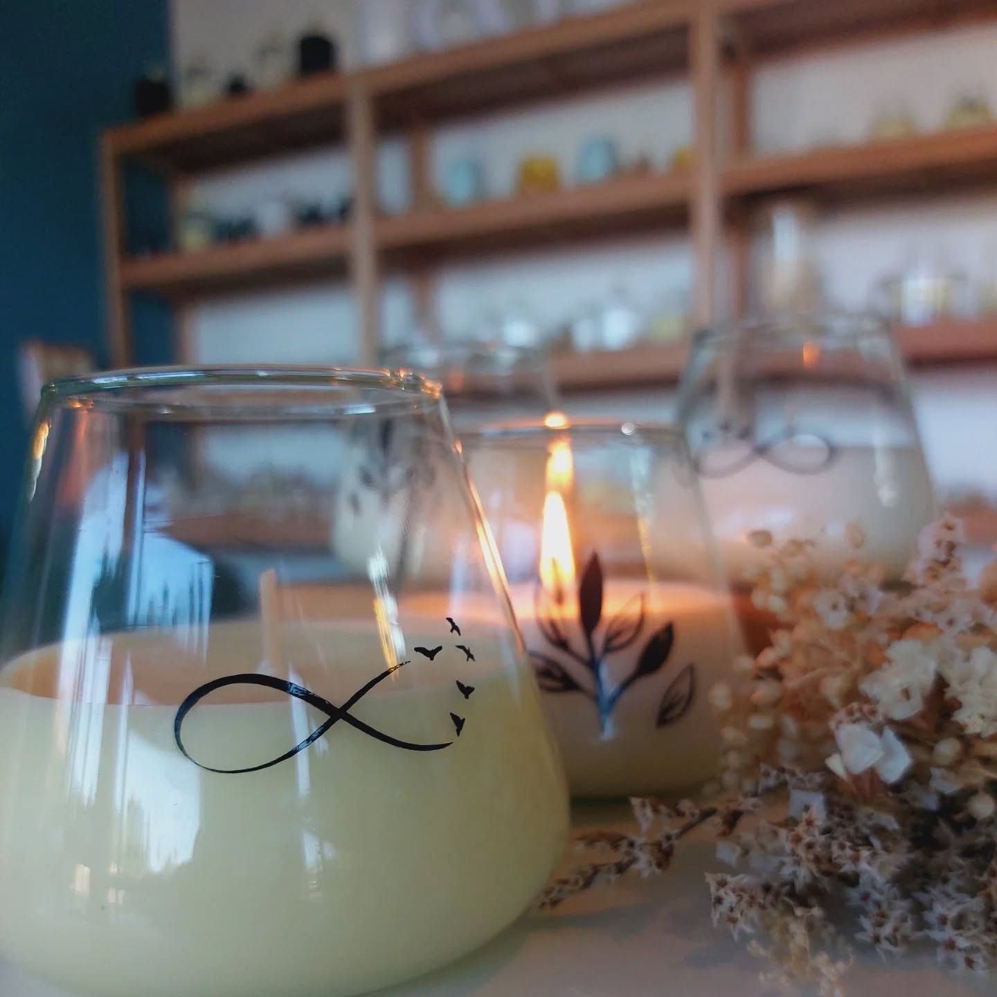 Velas encendidas en vasos decorativos, con símbolo de infinito y diseño floral.
