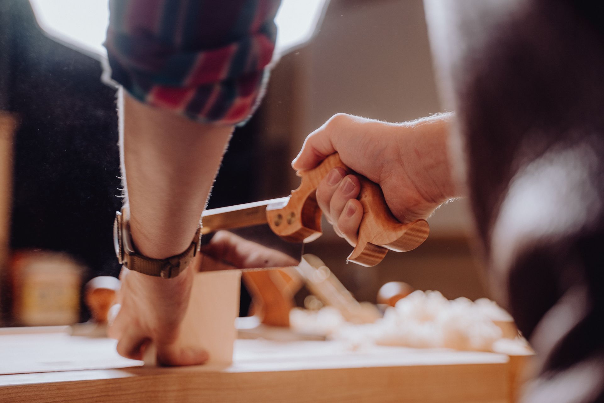 A skilled craftsman meticulously carves intricate patterns into a block of wood using a specialized woodworking tool.