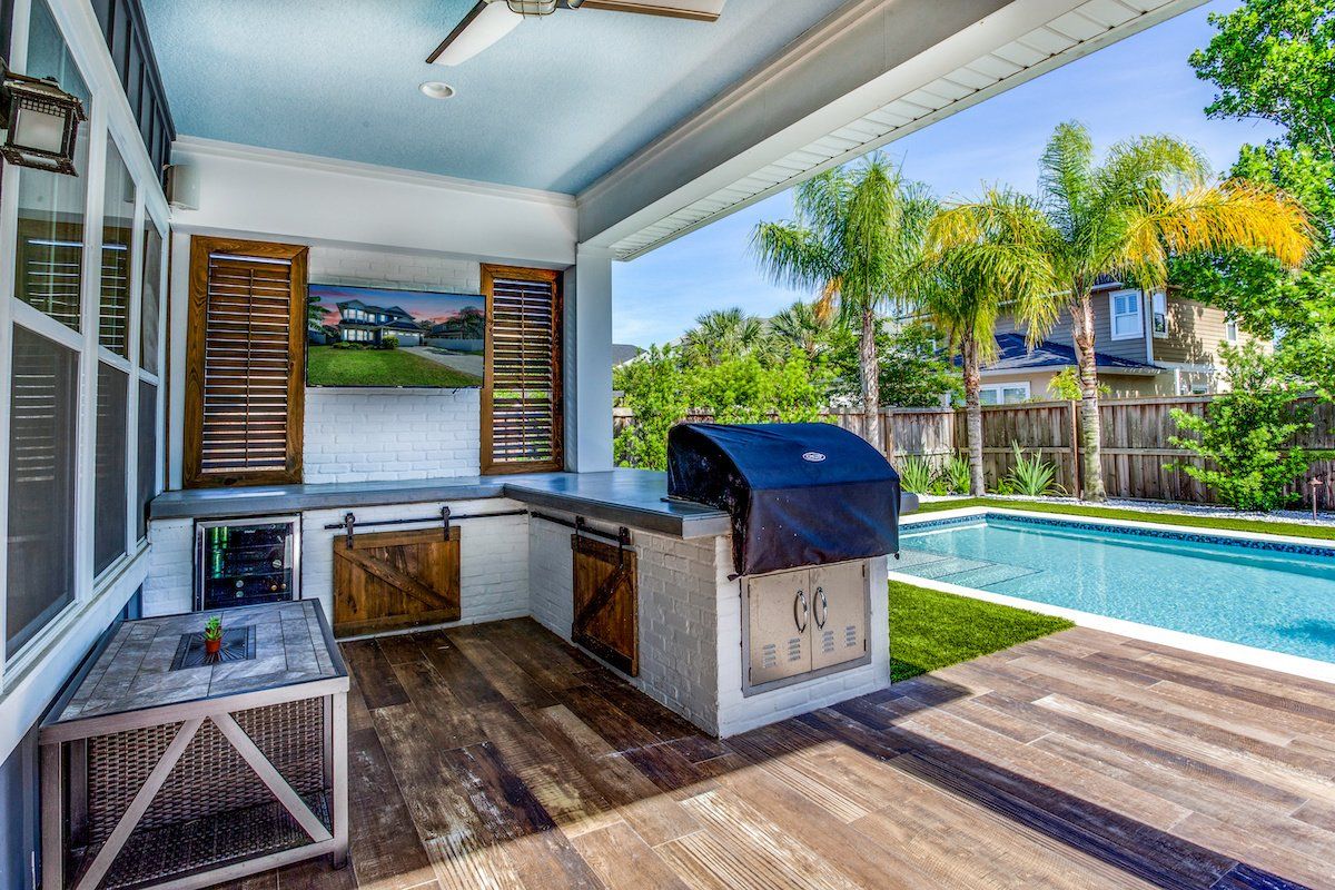 Inviting backyard oasis featuring a pristine pool surrounded by lush greenery and a stylish outdoor kitchen, perfect for relaxation and entertainment.