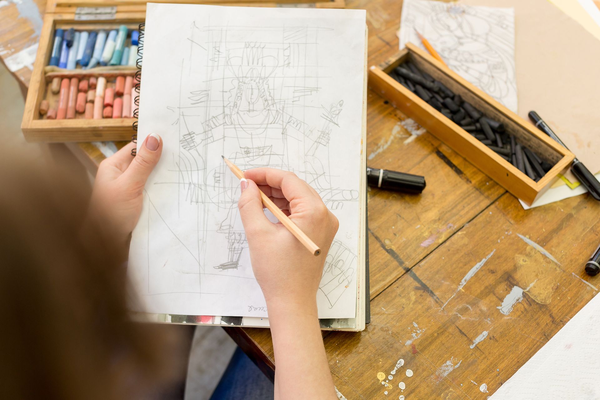 Hände halten Bleistift und skizzieren Architekturpläne auf weißem Papier. Künstlerbedarf aus Holz und Tisch.