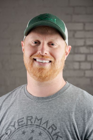 A man with a beard is wearing a green hat and a gray shirt.