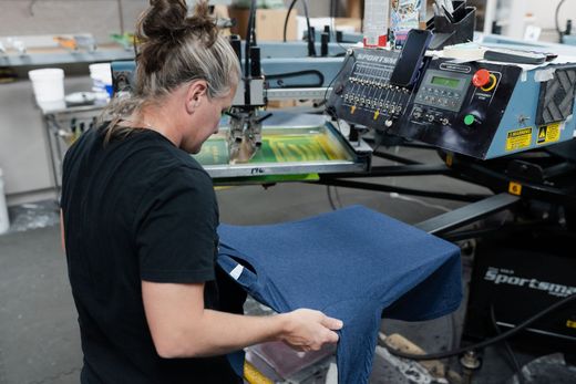 A woman is working on a screen printing machine in a factory.