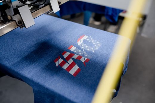 A t-shirt is being printed on a machine in a factory.