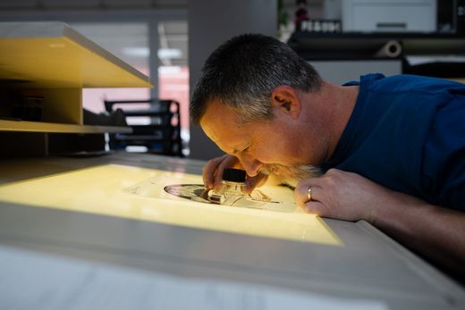 A man is looking at a picture with a magnifying glass.