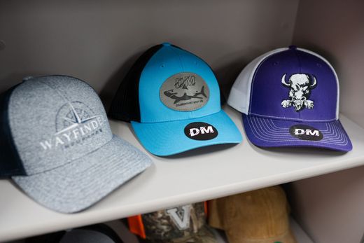 Three hats are sitting on a shelf in a closet.