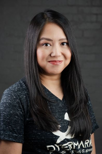 A woman with long black hair is wearing a black shirt and smiling.