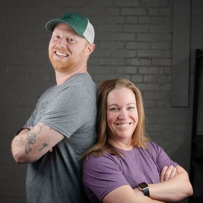 A man and a woman are standing back to back with their arms crossed.