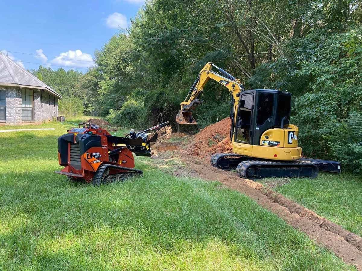 A yellow excavator is digging a hole in the dirt next to a red machine.