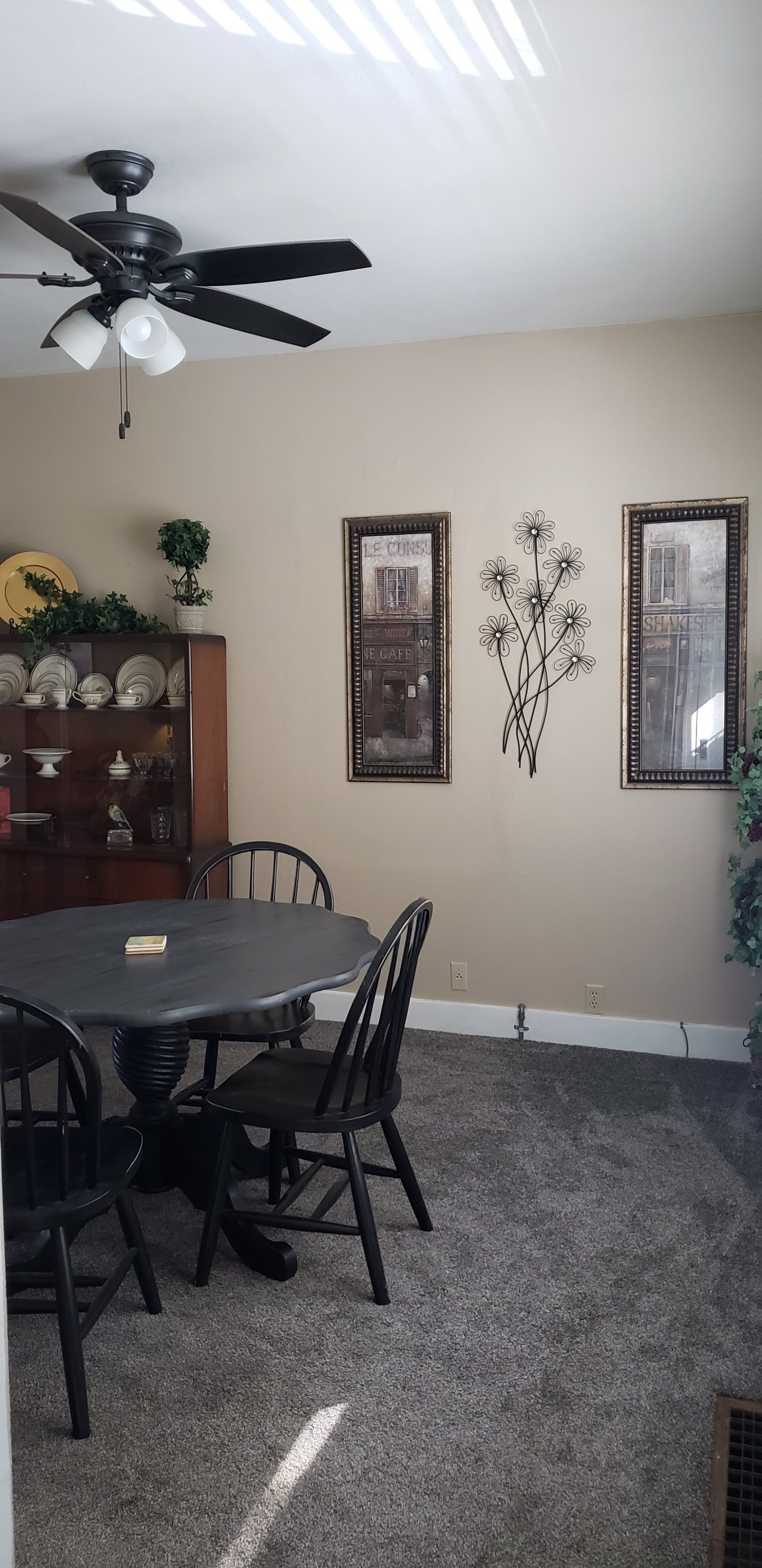 A dining room with a round black table, chairs, and decorations on the walls.