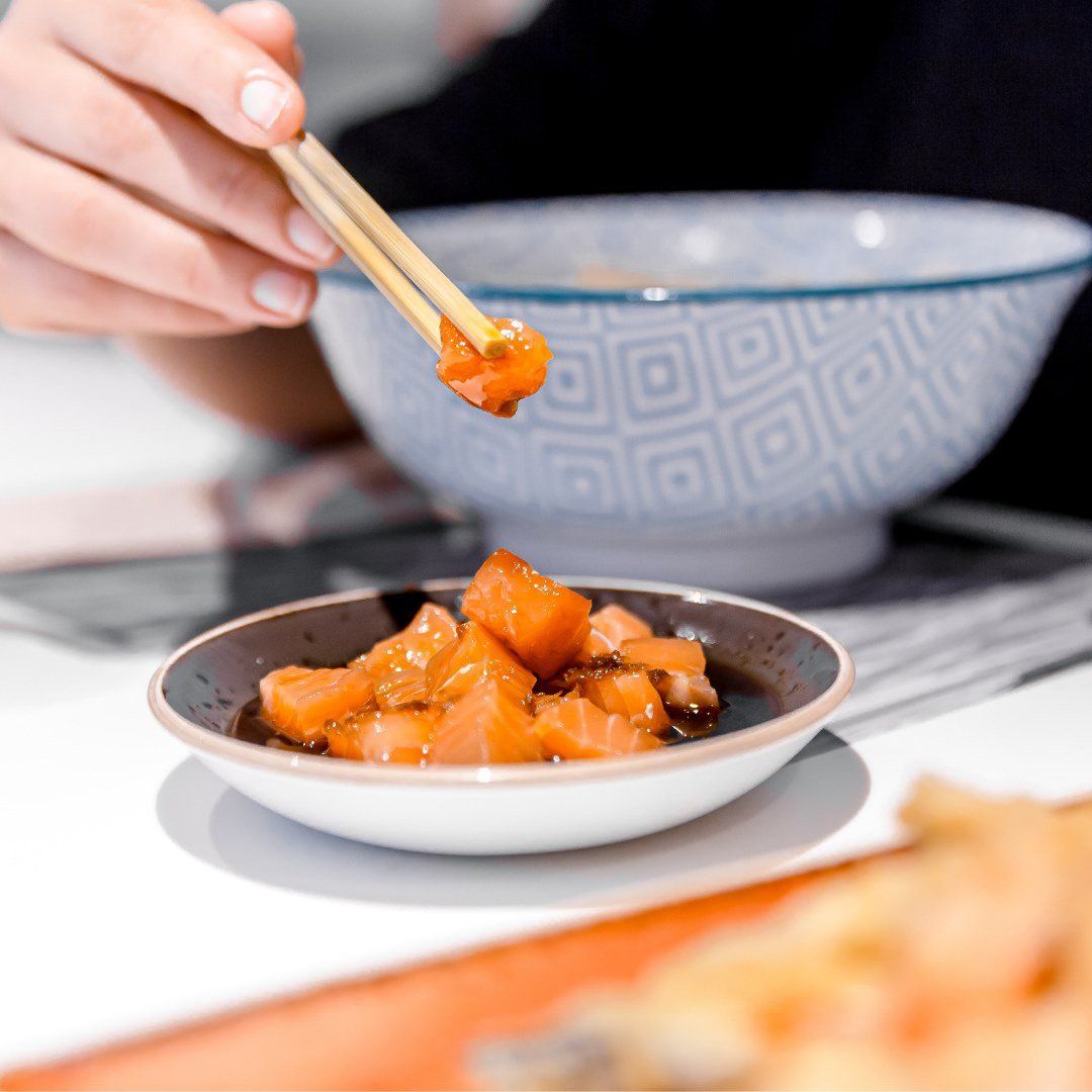 Una persona sostiene palillos sobre un recipiente con comida.